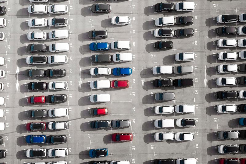 Vogelperspektive auf einen großen Parkplatz bei Gebrauchtwagen Ankauf Ingolstadt, der mit Reihen weißer Autos gefüllt ist.